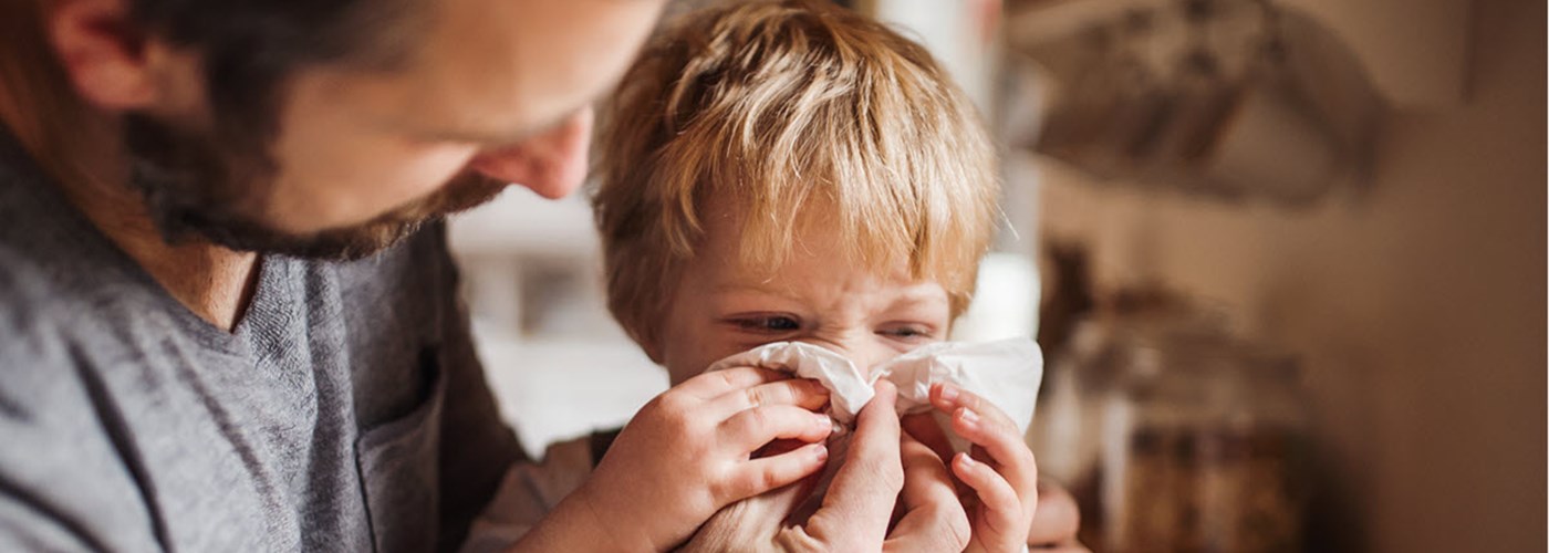 Father helping his young son blow his nose 
