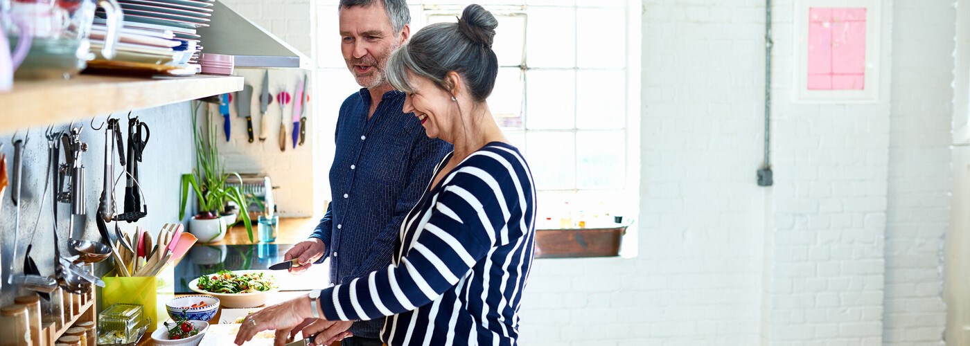 Middle aged couple laughing, making a healthy salad 