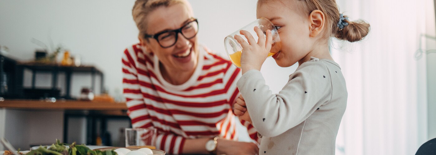 Cute Girl Drinking Juice at Breakfast with her Mom