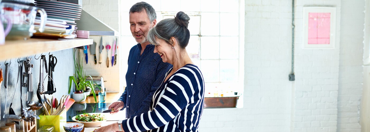 A couple of adults cooking a healthy meal, smiling