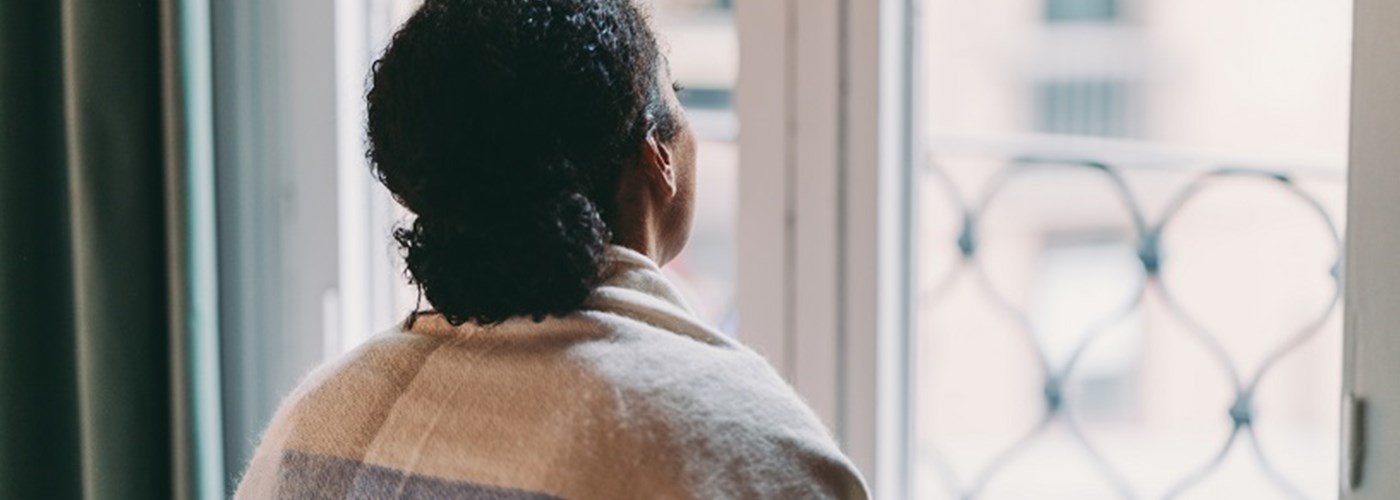 Young woman holding a coffee mug while looking through the window