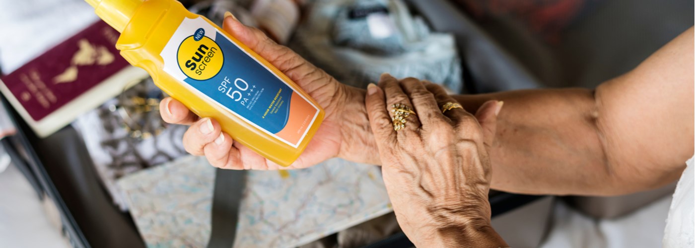 Hands of a woman holding a bottle of sunscreen lotion