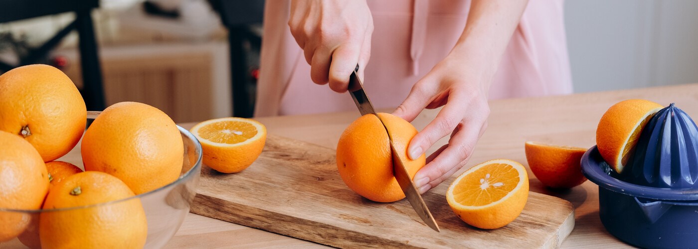 Woman makes orange juice at home, hands with oranges