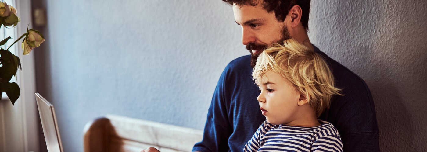Father and toddler looking up ear infection symptoms on laptop
