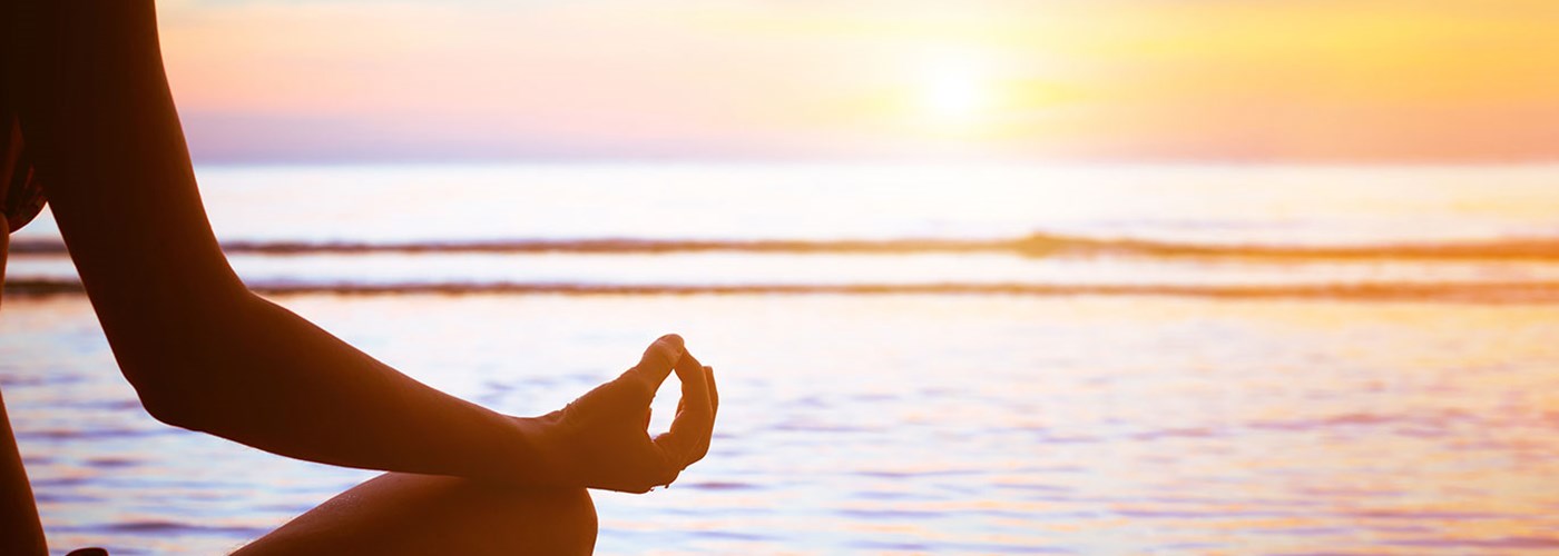 person meditating by the ocean