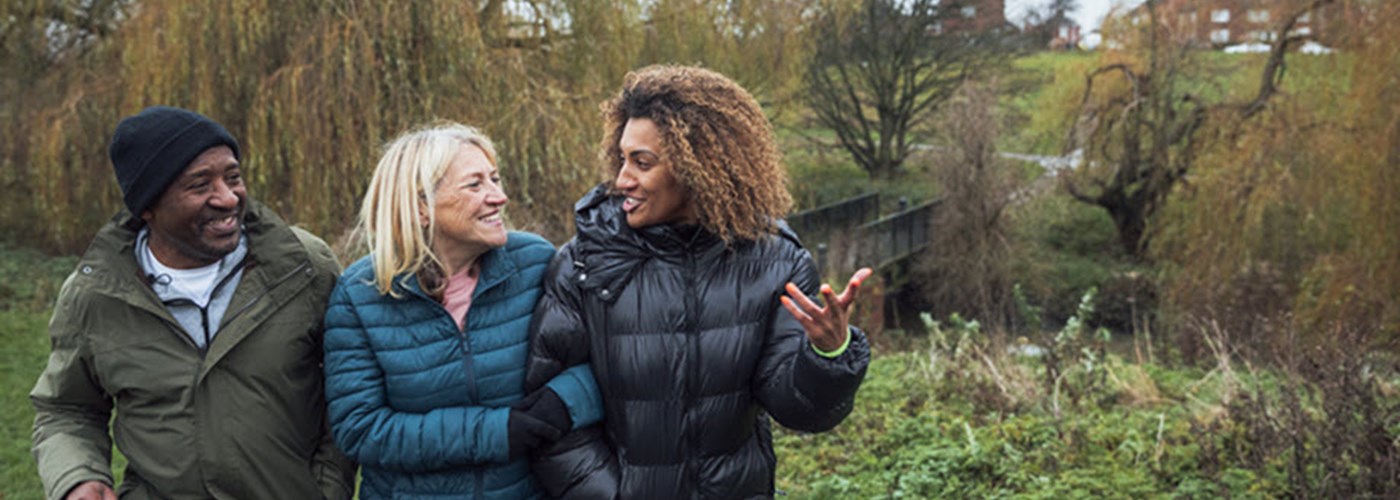 Two parents with their teenage son walking through a field in autumn 