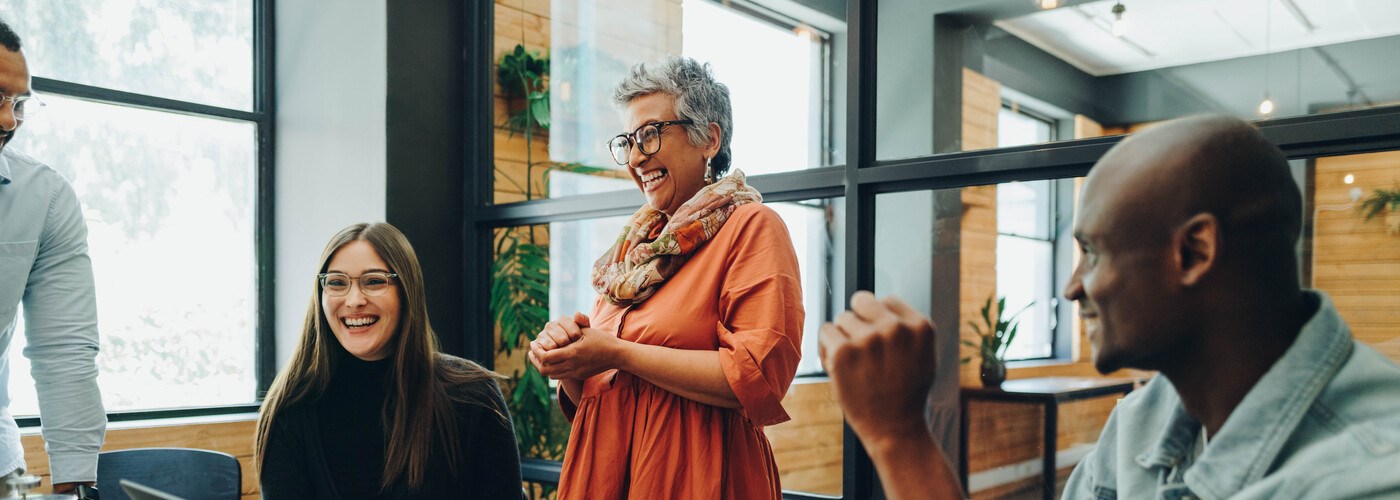 Multigenerational colleagues smiling cheerfully during an office meeting 