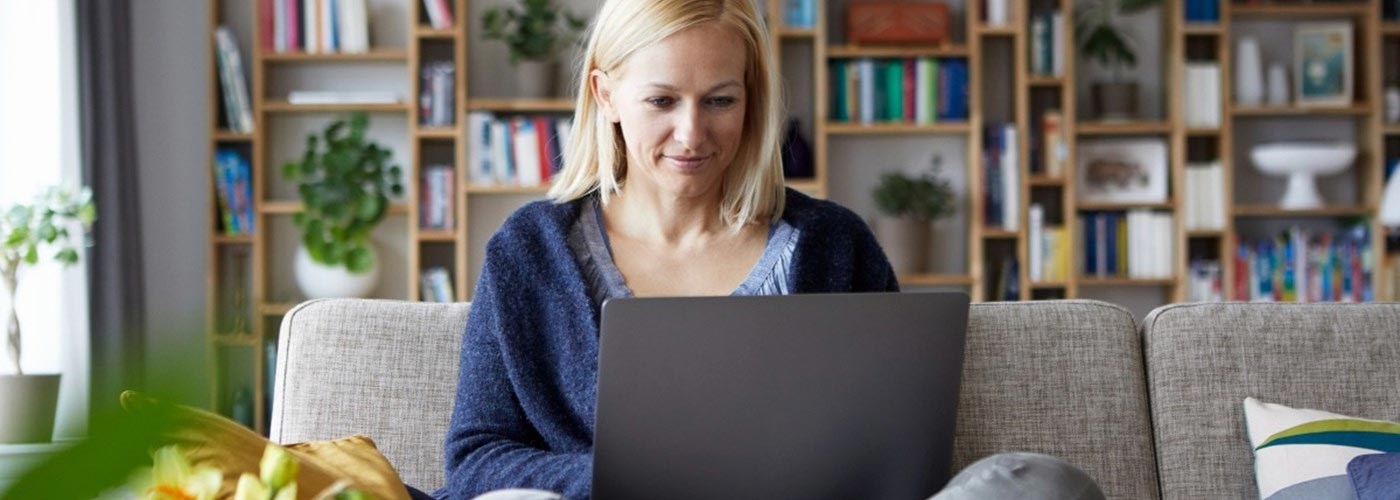 A woman is speaking to her GP on video call, sat in her living room