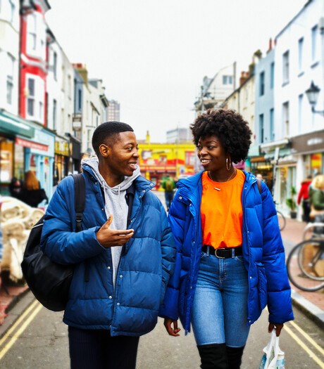 Couple of young adults walking in a town market street