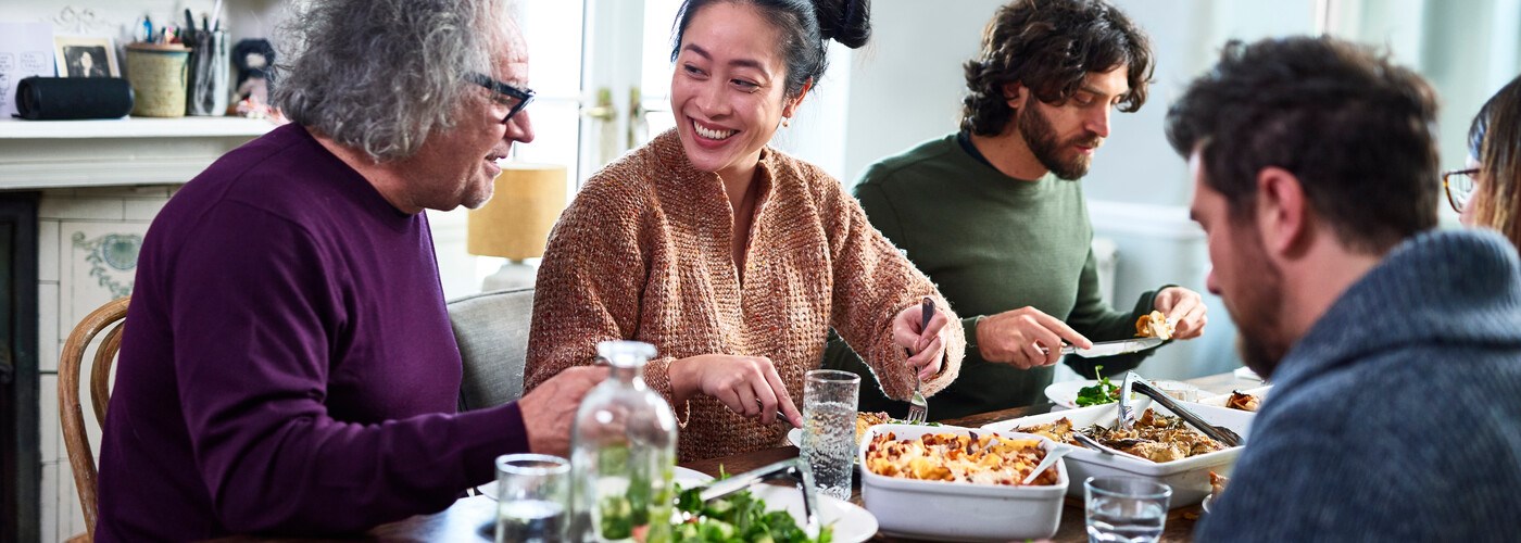 Group of mixed aged relatives sitting at dining table enjoying home cooked meal