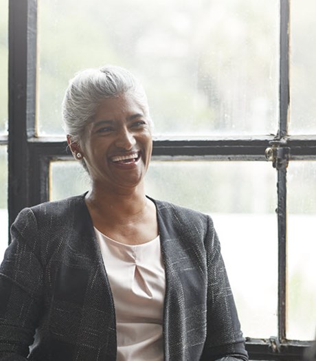 Middle aged lady in work attire smiling with two female employees 