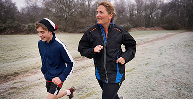 Mother and young son running outdoors in winter