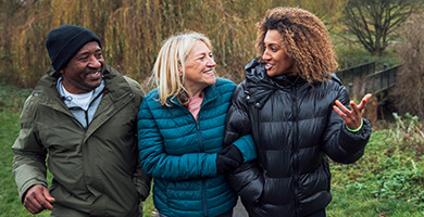 A man and two women talking, walking in woodlands